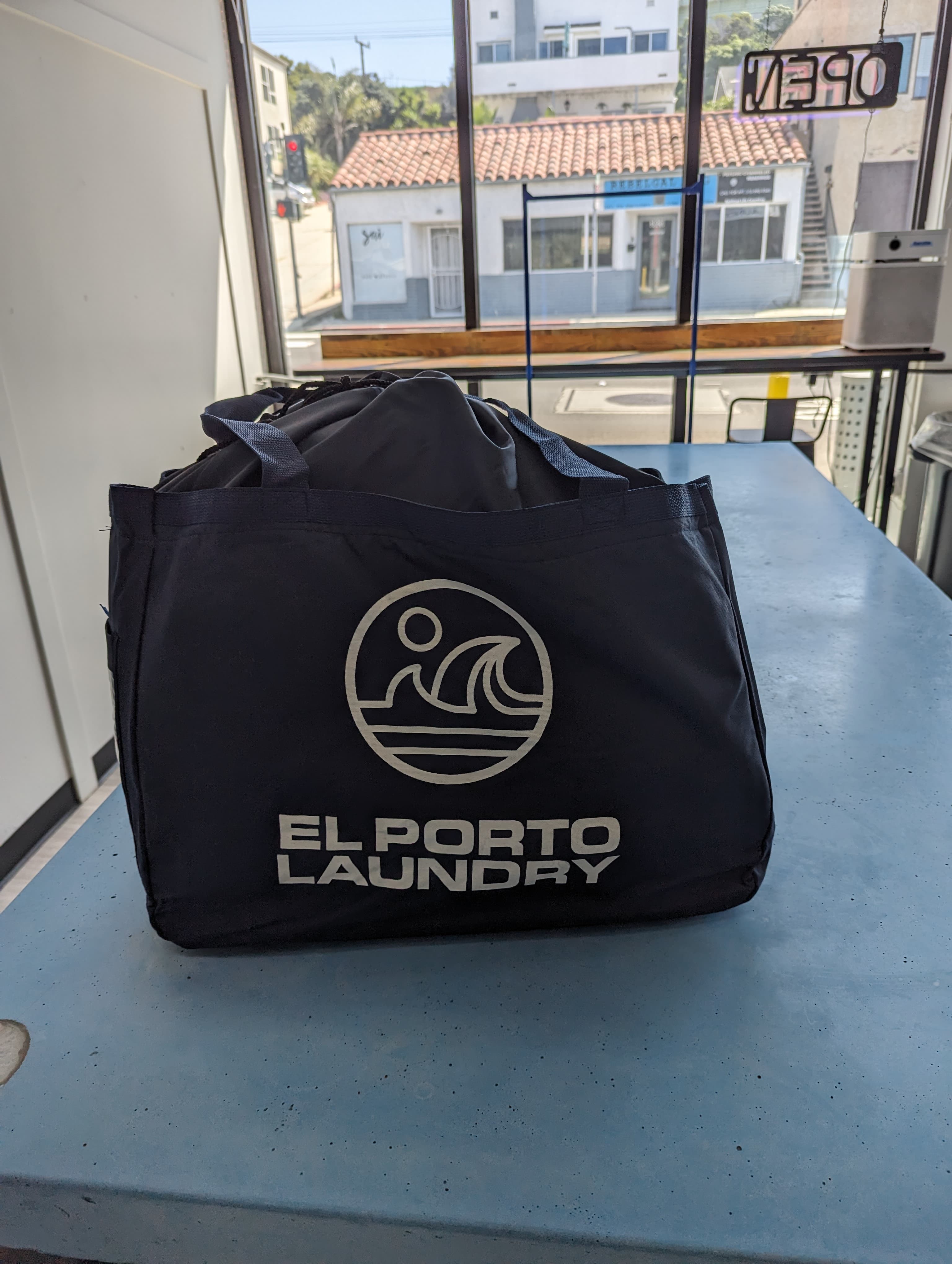 El Porto Laundry branded tote bag on the service counter at drop-off